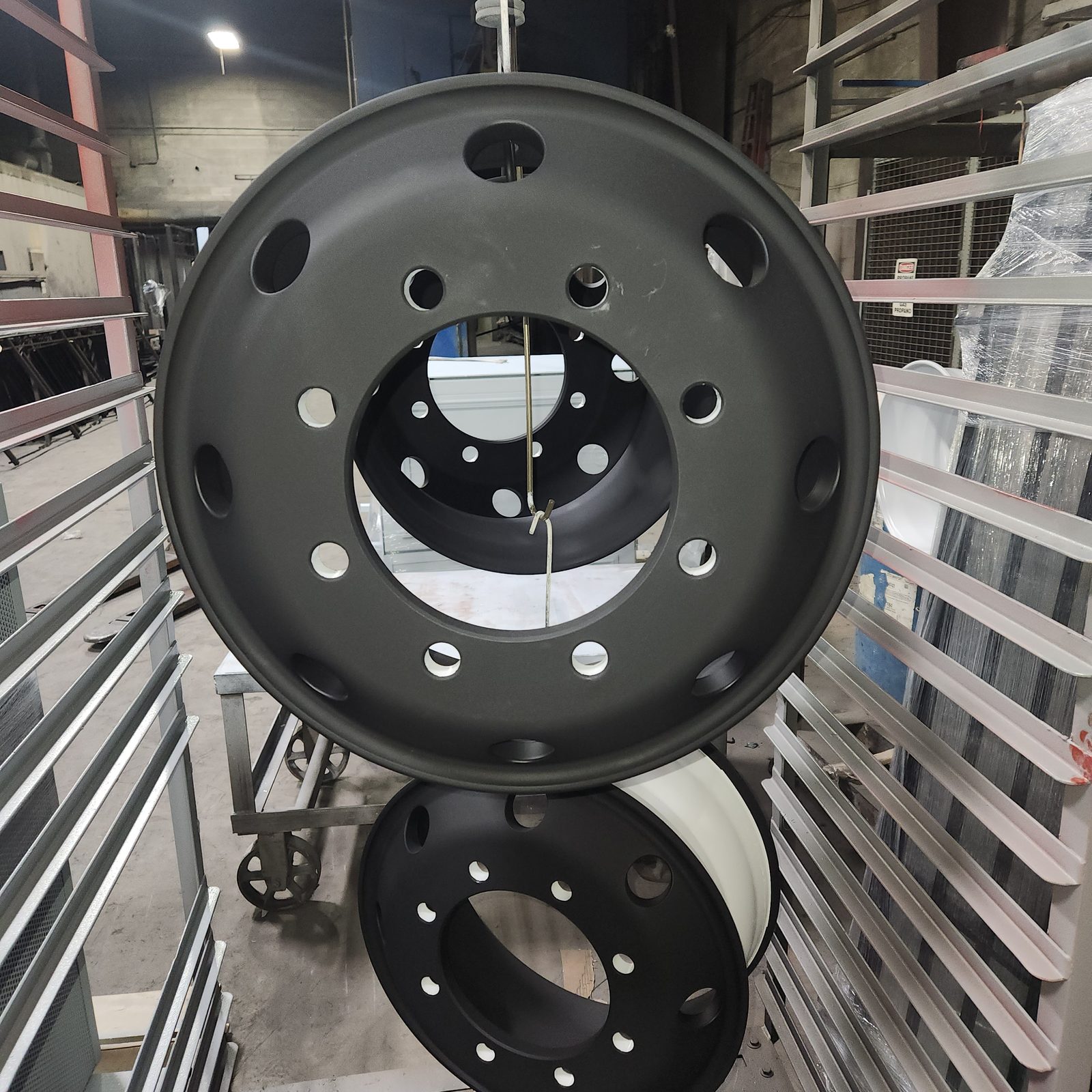 Freshly painted matte black heavy truck wheels hanging on the Toota Group paint line